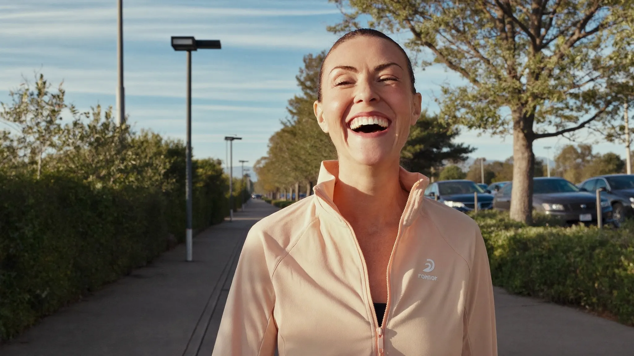 A woman in her late 40s laughing on a sunrise walk, full of energy